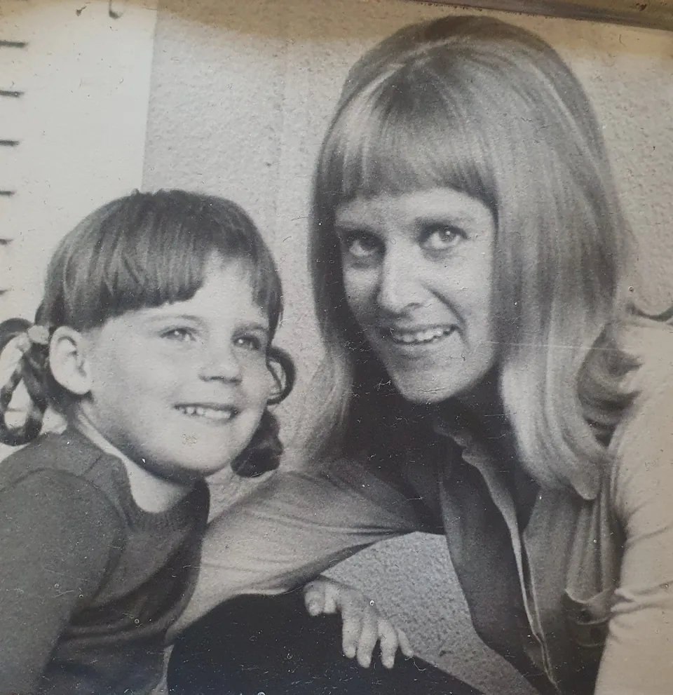Schwarz-Weiß-Foto von 1971: Katarina Schickling als Kind mit Zöpfen, lachend an der Seite ihrer Mutter